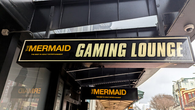 Signs for The Mermaid strip club adult entertainment and slot machine gaming lounge in capital city of Wellington, New Zealand Aotearoa - taken on 23 August 2024