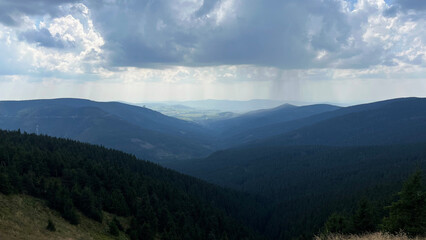 Rain clouds with rain over forested mountains. View from above. Sudeten Mountains. Czech Republic