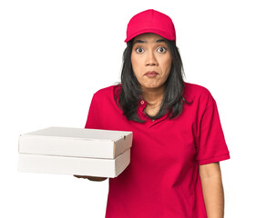 Latina delivering pizza, studio setup shrugs shoulders and open eyes confused.