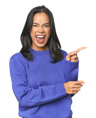 Simple portrait of a young Latina pointing with forefingers to a copy space, expressing excitement and desire.