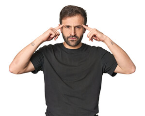 Studio portrait of young Hispanic male focused on a task, keeping forefingers pointing head.