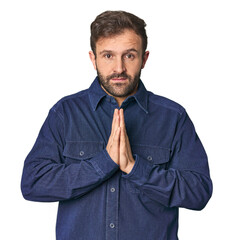 Studio portrait of young Hispanic male praying, showing devotion, religious person looking for...