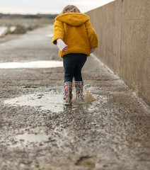 Child splashing in a puddle of rain near the beach