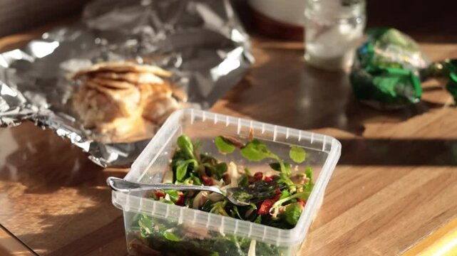 Healthy salad in a tupper ware on a rustic wooden table. Homemade take-away food.