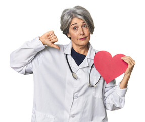 Caucasian mid-age doctor with heart symbol showing a dislike gesture, thumbs down. Disagreement concept.