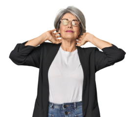 Caucasian mid-age female in business suit feeling confident, with hands behind the head.