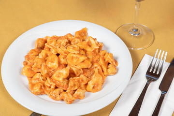 Tortellini al ragù plate
Delicious tortellini in a rich ragù sauce served on a white plate, accompanied by a glass of wine and cutlery.