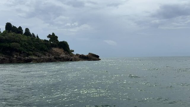 Blue shiny sea waves and rocky coast.