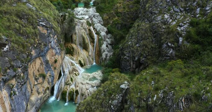 Beautiful drone shot of with drone of a clean turquoise waterfall between mountains with vegetation in Millpu, Ayacucho in Peru.