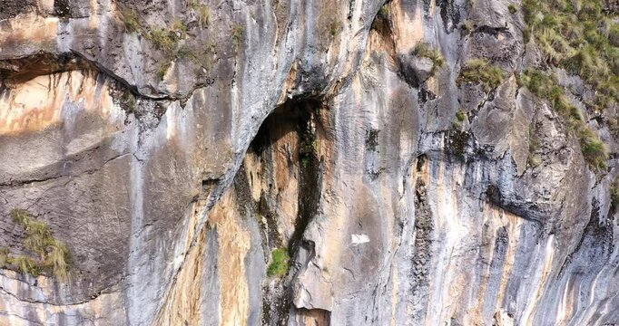 Beautiful drone shot around some rock mountains with cave entrances on a hot afternoon.