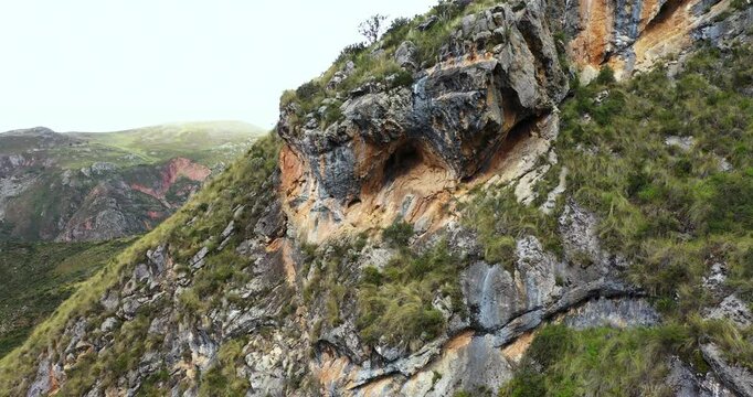 Beautiful shot with drone zoom in to a cave on top of a mountain with vegetation in Millpu located in Ayacucho, Peru.