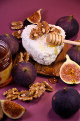 Whole and cut figs with cottage cheese and honey on a purple background. Mediterranean cuisine