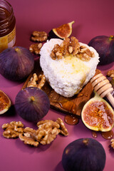 Fototapeta premium Whole and cut figs with cottage cheese and honey on a purple background. Mediterranean cuisine