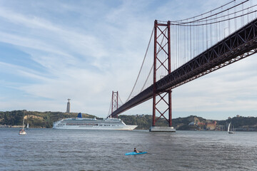 Naklejka premium Cruise ship passing under the 25 de abril bridge in lisbon