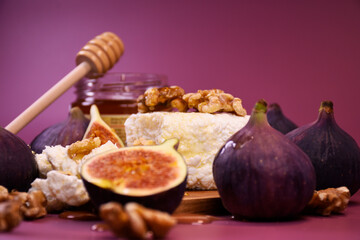 Whole and cut figs with cottage cheese and honey on a purple background. Mediterranean cuisine