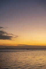 a beautiful sunset with a lone fisherman fishing on a far away sea