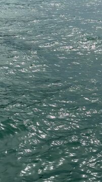 Blue glittering sea waves, vertical video.