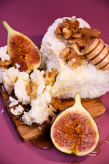 Whole and cut figs with cottage cheese and honey on a purple background. Mediterranean cuisine