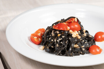 Cuttlefish ink fettuccine with shrimp and calamari.
Gourmet dish of cuttlefish ink tagliatelle with fish