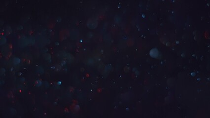 Vibrant red and blue dust particles with bokeh lens blur and glowing trails against a black background, creating a dynamic and cosmic atmosphere.