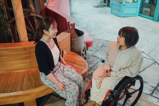 夜に車椅子に乗った日本人女性が友人と夏の沖縄旅行を楽しんでいる