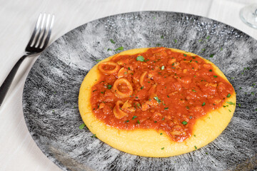 Polenta dish with fish sauce.
Typical traditional Italian dish, polenta with fish sauce, calamari, shrimp and clams