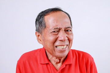 Fototapeta premium Displeased senior Asian man in red t-shirt isolated on white background