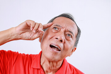 Thoughtful Asian old man standing while touching head isolated on white background