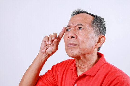 Thoughtful Asian old man standing while touching head isolated on white background - Powered by Adobe