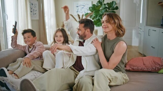 Carefree family having fun playing at couch. Parents children tickling on sofa