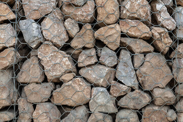 Stone wall background or texture. Building strengthening. Stones in the iron grid on texture