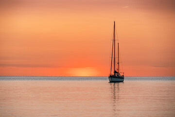 Fototapeta premium Silhouette Of A Pleasure Boat During A Beautiful Sunrise On Threflenean Sea In The Harbor Of The Coastal And Tourist Town Of Collioure (Cotlliure). France. Orange Sky.