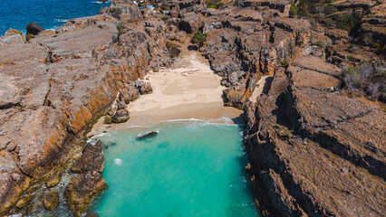 Stunning coastal vista with rugged rocks and shimmering turquoise waves, perfect for a serene ocean backdrop.