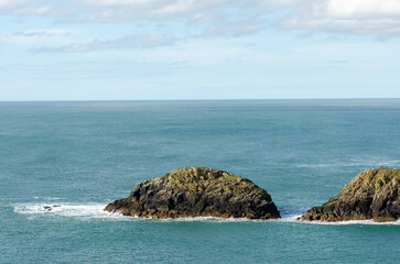 Naklejka premium Small rocky islands in the middle of a calm sea under a bright sky in Wales.