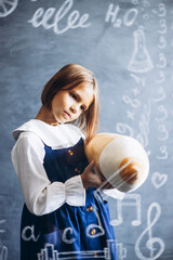 Fototapeta premium Cute little schoolgirl standing behind the glass board signed with math formulas