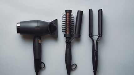Flat lay of a hair dryer, straightener, and triple curling iron on a light grey surface, Hairdresser’s essential tools featuring high-end devices for perfect hairstyling results.