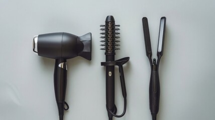 Flat lay of a hair dryer, straightener, and triple curling iron on a light grey surface, Hairdresser’s essential tools featuring high-end devices for perfect hairstyling results.