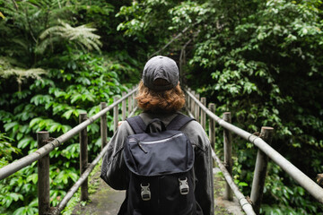Fototapeta premium Solo Female Traveler Hiking Through Lush Jungle on Elevated Pathway.