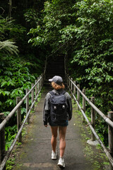 Solo Female Traveler Hiking Through Lush Jungle on Elevated Pathway.