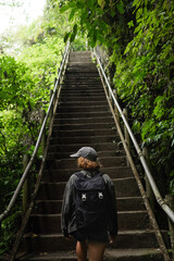 Solo Female Traveler Hiking Through Lush Jungle on Elevated Pathway.