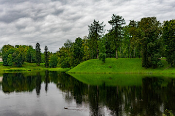 picturesque view of a park with a pond in cloudy weather