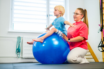 Young boy with female physical therapist exercising during therapy session. Child physical therapy....