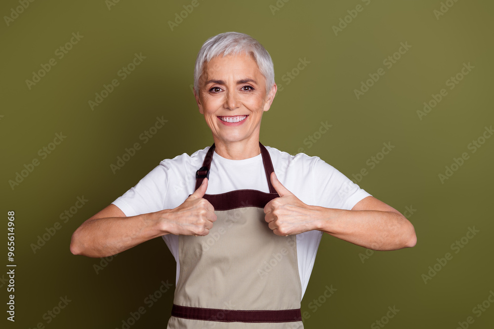 Sticker Photo of shiny attractive lady dressed apron preparing drinks showing two thumbs up empty space isolated green color background