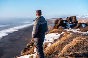 Man watches the sunset from a hill on Dyrholaey beach in Iceland