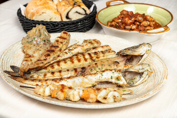 Mixed grill of fresh fish served on a large oval white restaurant plate.