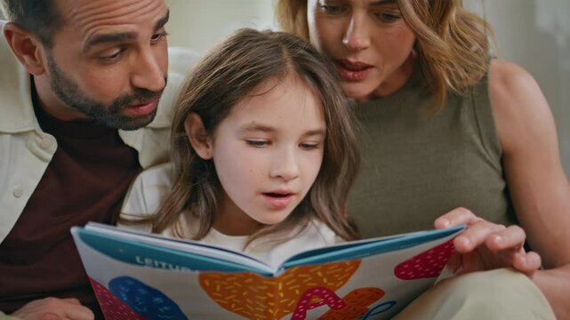 Interested parents daughter reading book weekend closeup. Happy family relaxing