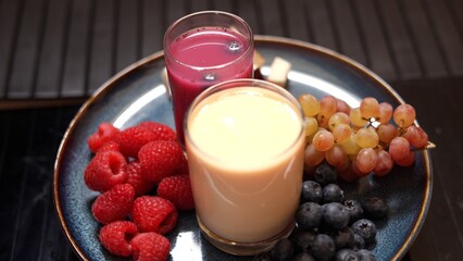 Assorted fruits, glasses of juice on plate placed on wood table emphasize eco-friendly eating. Nutrient-rich meal supporting plant-based diets, healthy living, and sustainable choices.
