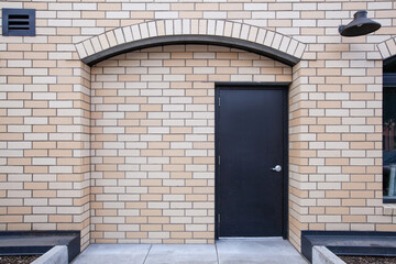Brick wall facing stone facade of residential building in city center, with black door. High quality picture for download