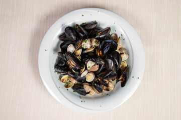 Mussels and clams soup in a withe dish.