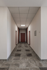 empty long corridor with red brick walls and doors in interior of modern apartments or office